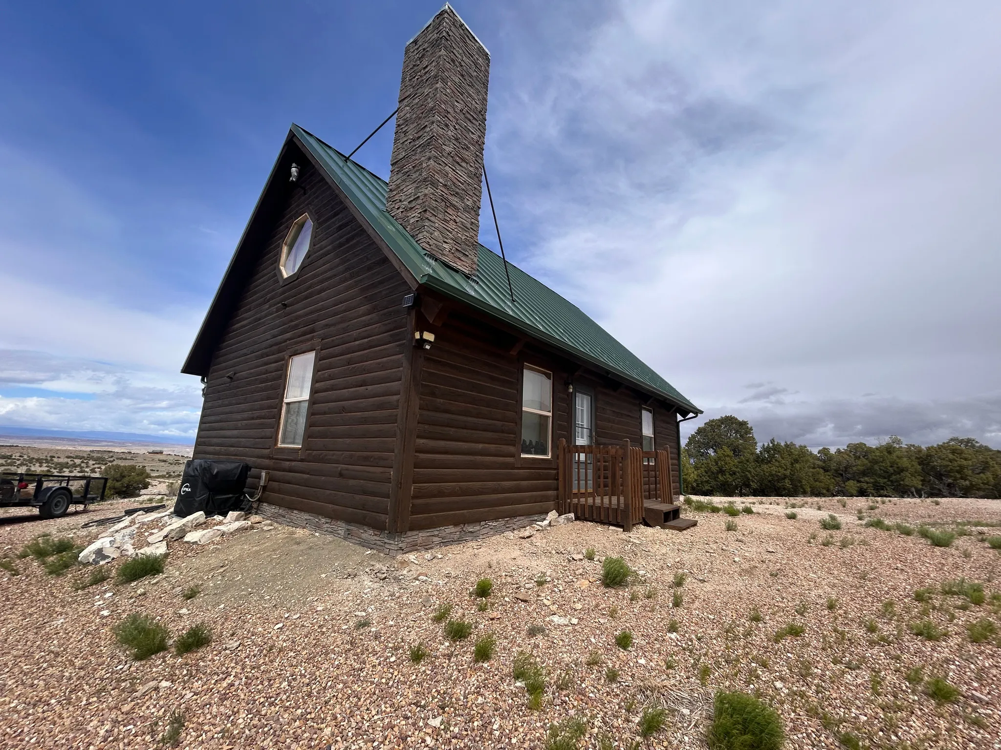 Log cabin exterior with a green metal roof and a prominent stone chimney