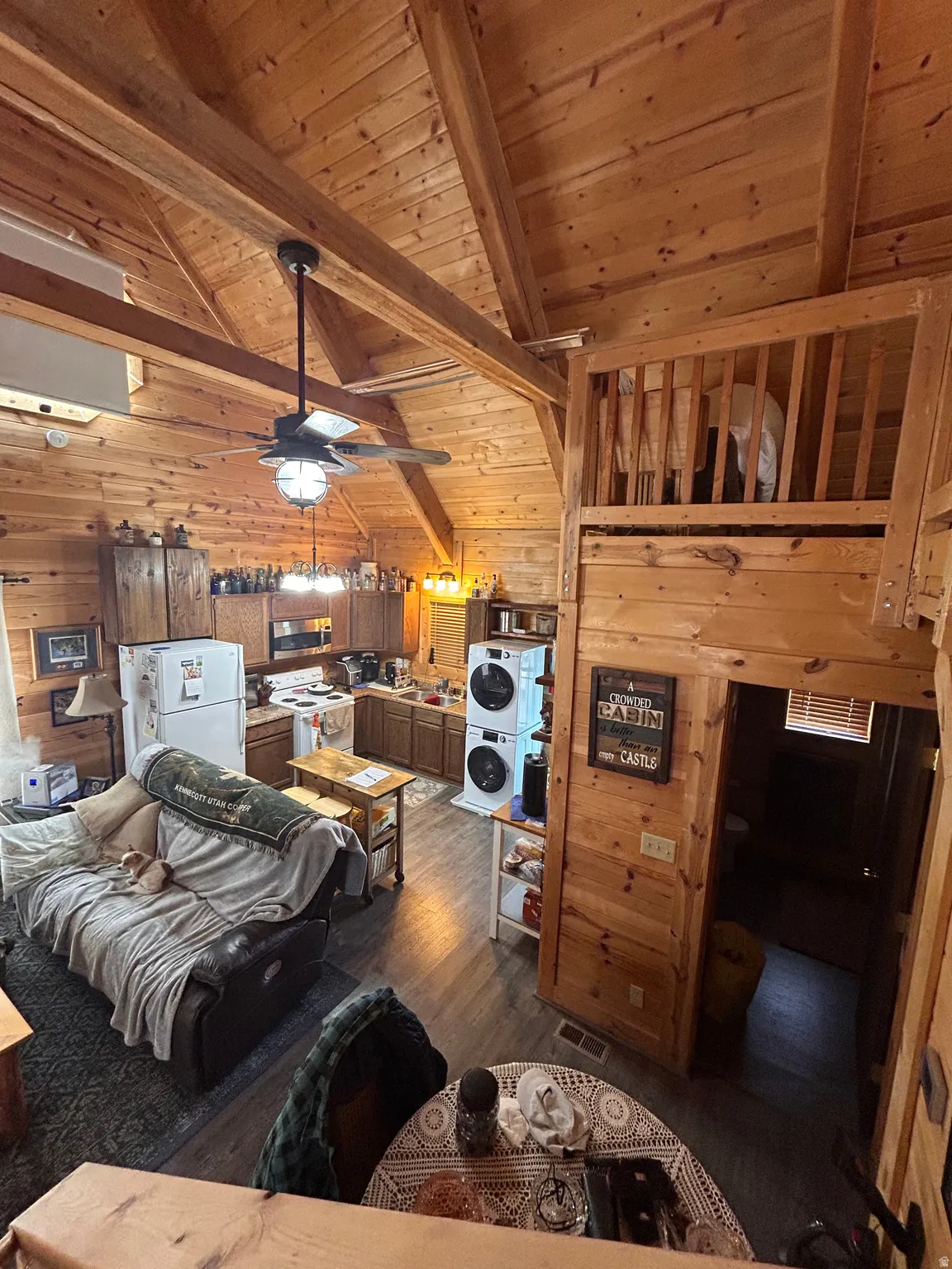 Open-concept living space with extensive wood paneling and exposed ceiling beams