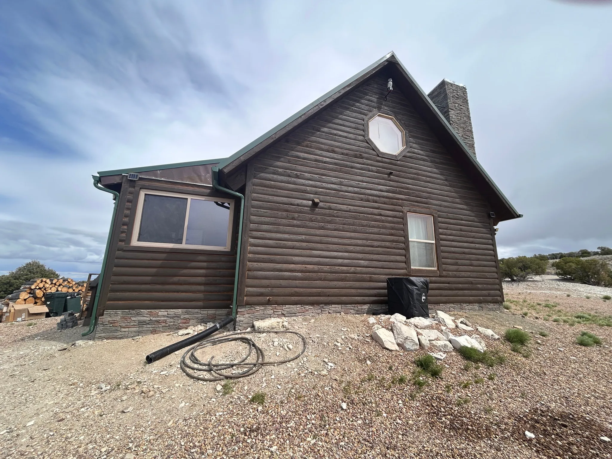 Log-sided exterior with a stone chimney and stone foundation detailing