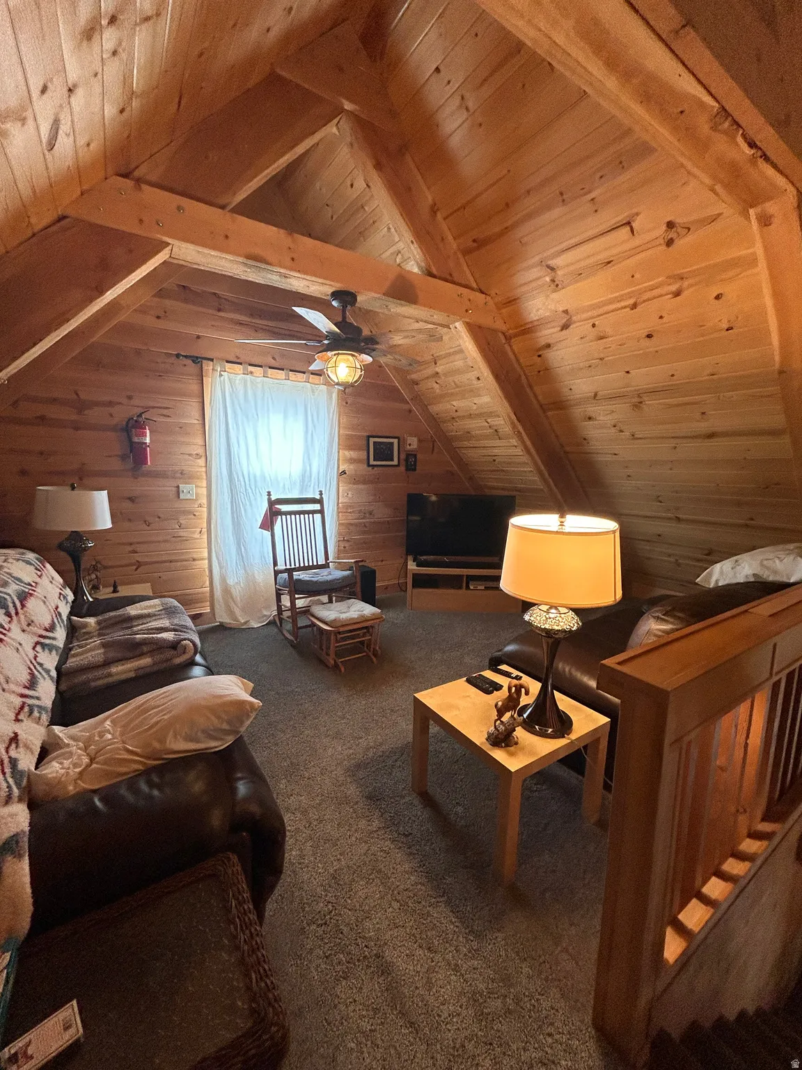 Attic living space featuring vaulted wood-plank ceilings, exposed wood beams, and textured carpeting