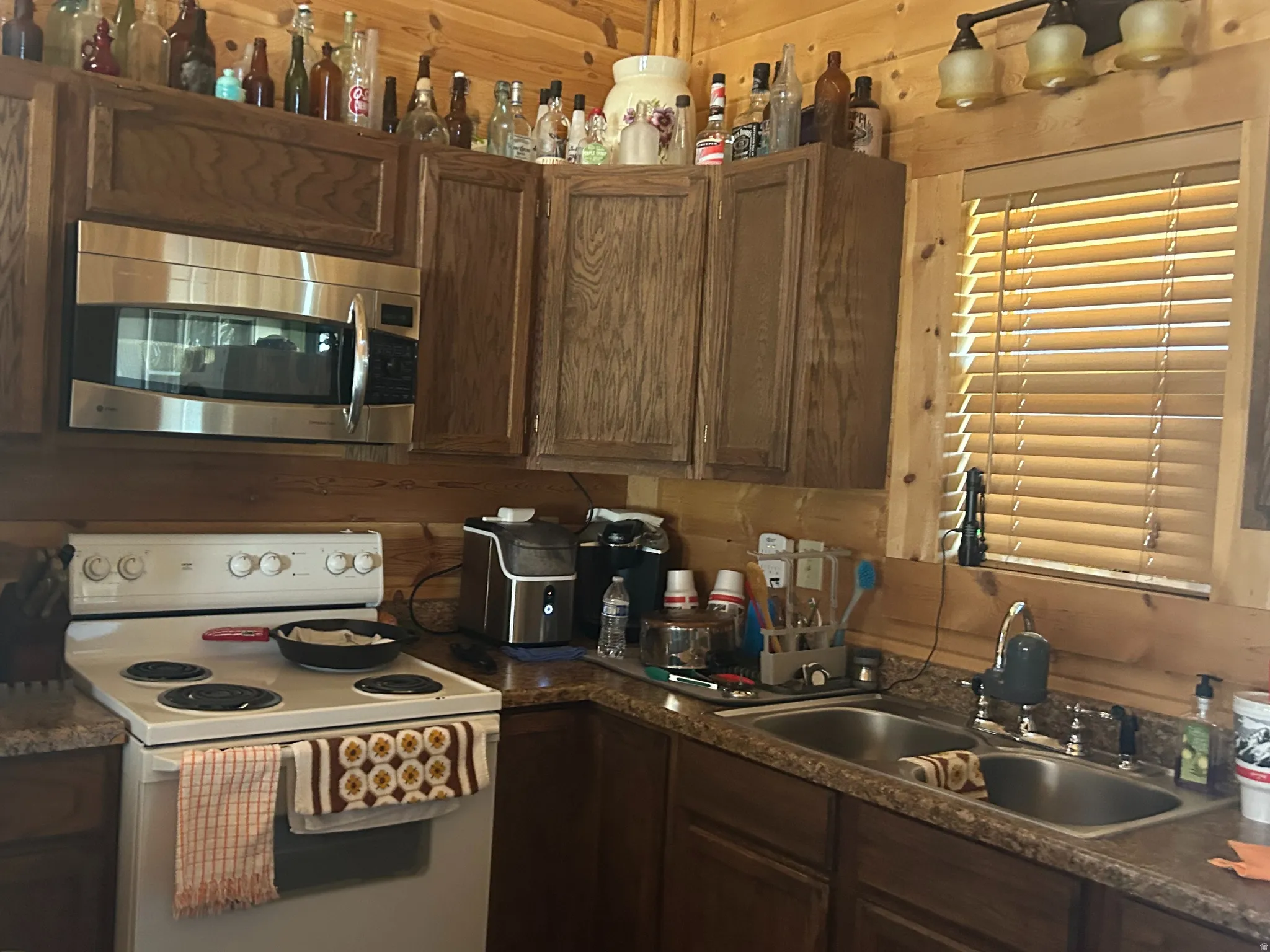 Galley kitchen featuring wood-finish cabinetry, stainless steel microwave, and a double basin sink