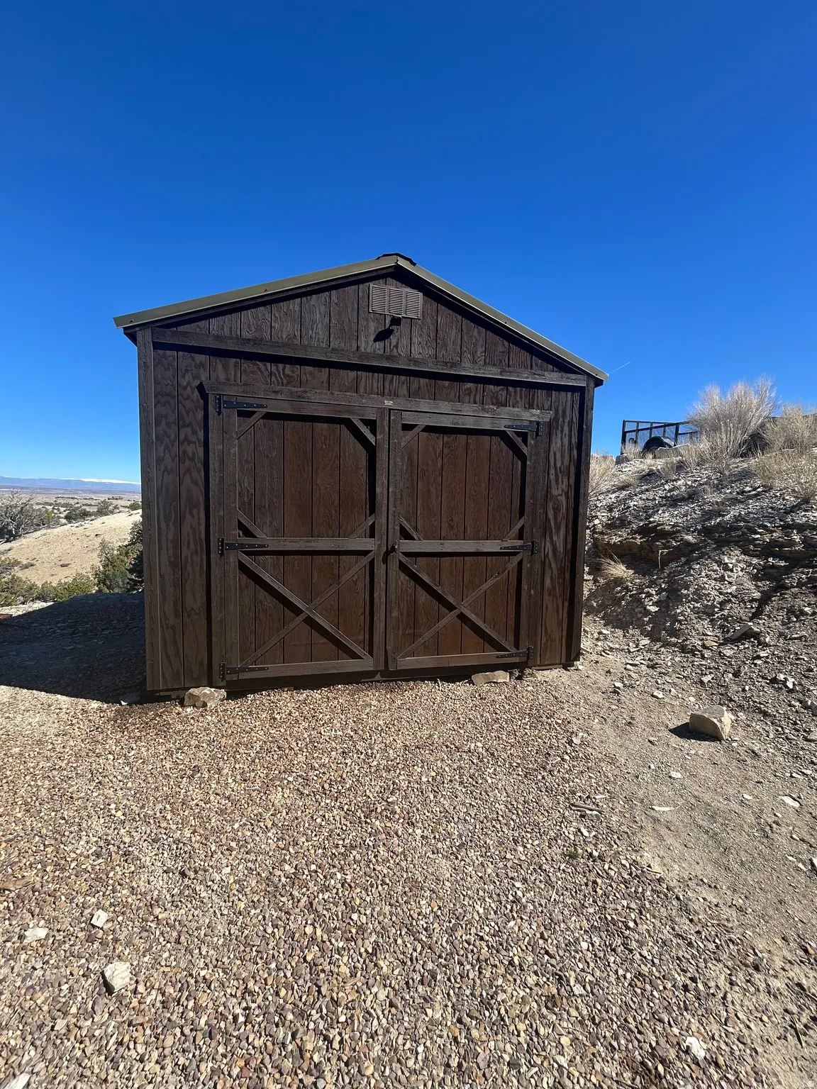 Wood-sided storage shed featuring double barn doors and a gable roof