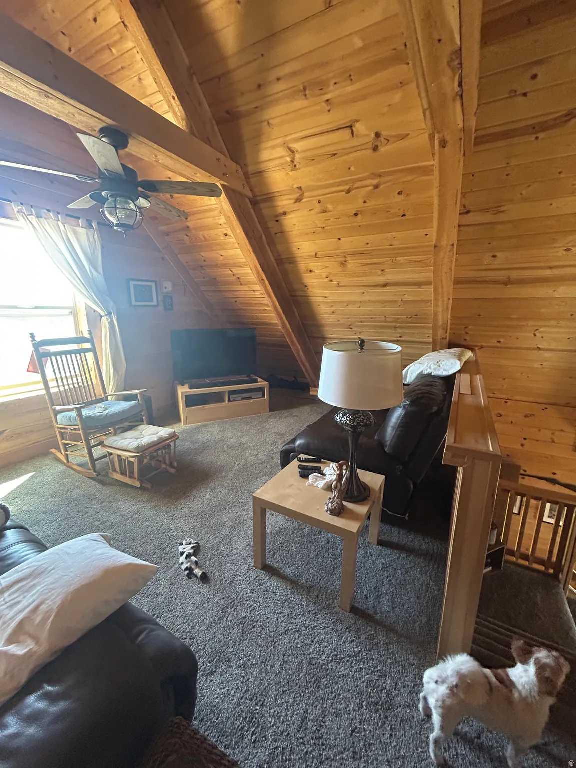 Vaulted wood-paneled ceilings with exposed wood beams, featuring a ceiling fan with integrated lighting