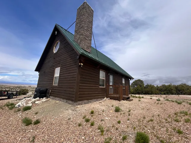 Log cabin exterior with a green metal roof and a prominent stone chimney