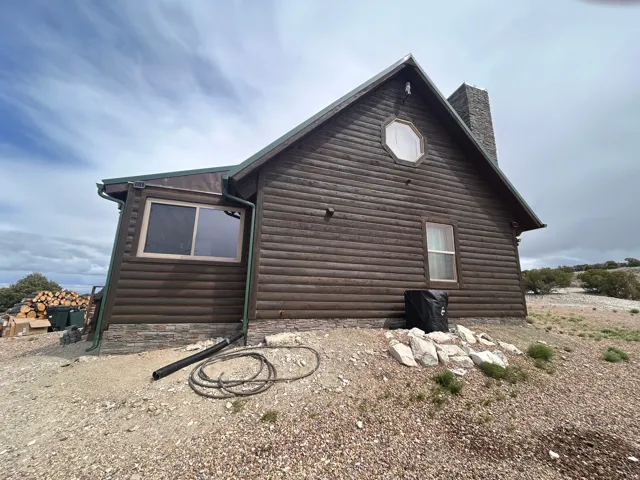 Log-sided exterior with a stone chimney and stone foundation detailing