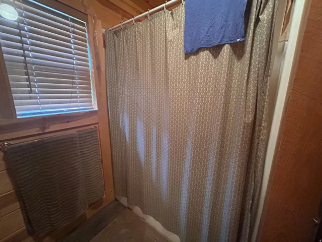 Shower enclosure with a patterned curtain, set against wood-finish wall paneling