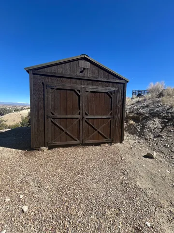 Wood-sided storage shed featuring double barn doors and a gable roof