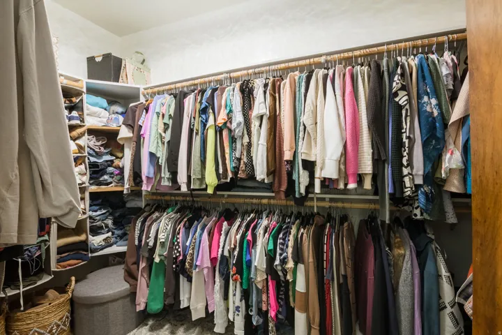 Walk-in closet featuring multiple hanging rods, built-in shelving, and white wall finishes