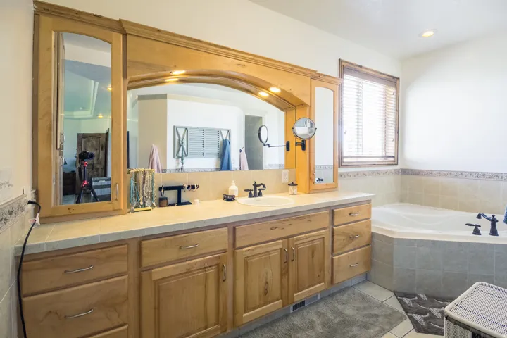 Bathroom vanity with wood cabinetry, an integrated sink, and a light-toned countertop