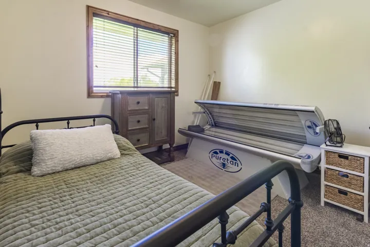 Room featuring light-colored walls, a window with horizontal blinds and wood trim, and textured carpeting