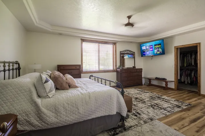 Spacious room featuring wood-finish flooring, a tray ceiling, and a ceiling fan
