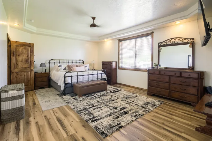 Spacious room featuring wood-finish flooring, a tray ceiling with recessed lighting, and a ceiling fan