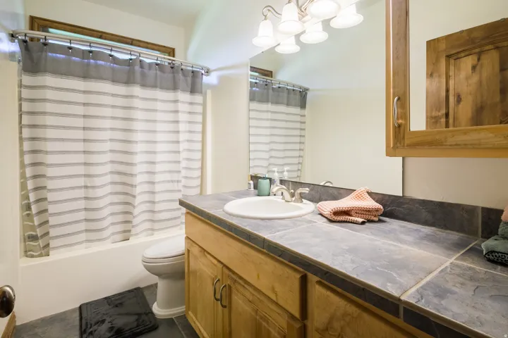 Bathroom vanity featuring a tiled countertop, undermount sink, and wood-finish cabinetry