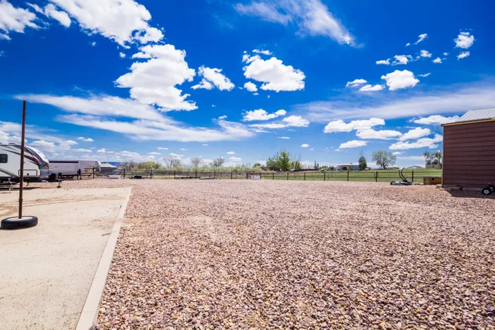 Expansive gravel lot with a visible boundary marker and a brown storage shed