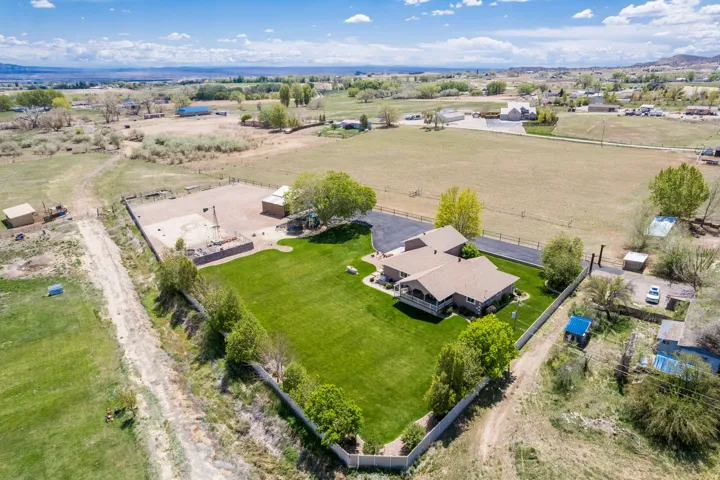 Expansive property featuring a single-story residence with a covered porch, a large manicured lawn, and paved driveway