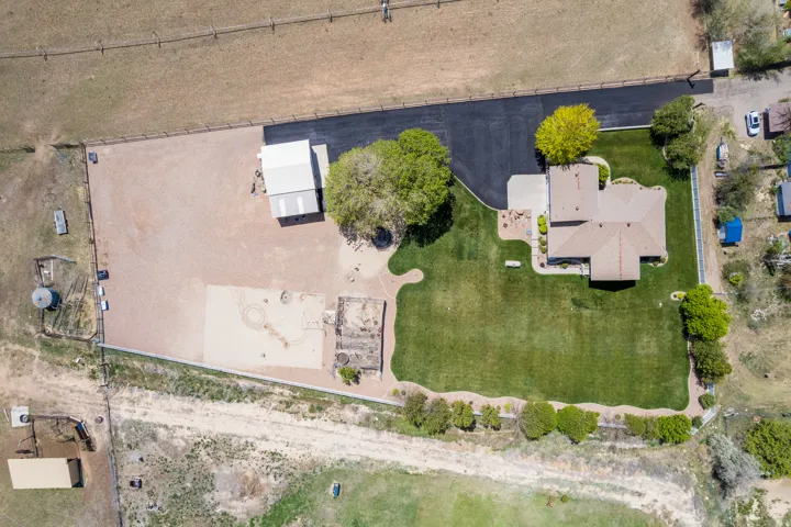 Expansive property featuring a single-story residence with a tan roof, a large paved driveway, and an extensive green lawn