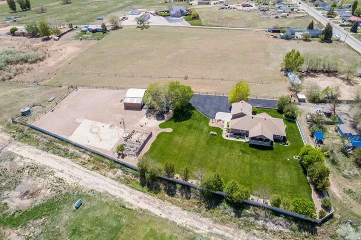 Expansive property featuring a large residence, separate outbuilding with metal roof, extensive gravel area, and a significant lawn space