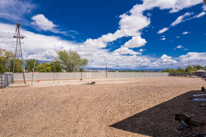 Expansive gravel yard featuring a decorative windmill structure and a full-length perimeter fence