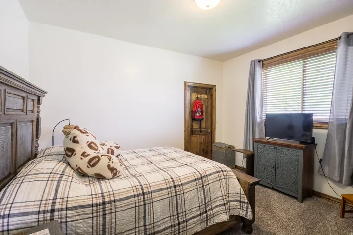 Carpeted room featuring a wood-finish door, wood-trim window with blinds, and recessed lighting