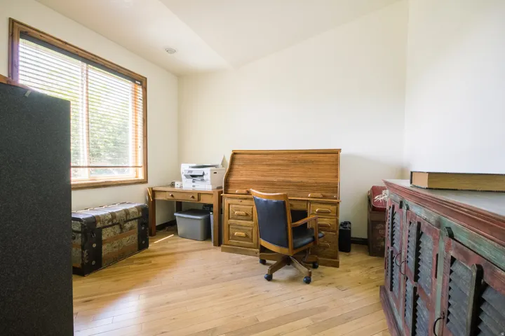 Sun-filled interior room featuring wood-finish flooring, a large window with wood trim, and recessed ceiling lighting