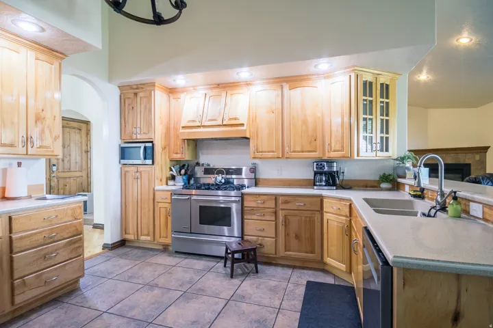 Kitchen featuring light wood cabinetry, stainless steel appliances, a double basin sink, neutral countertops, and tile flooring