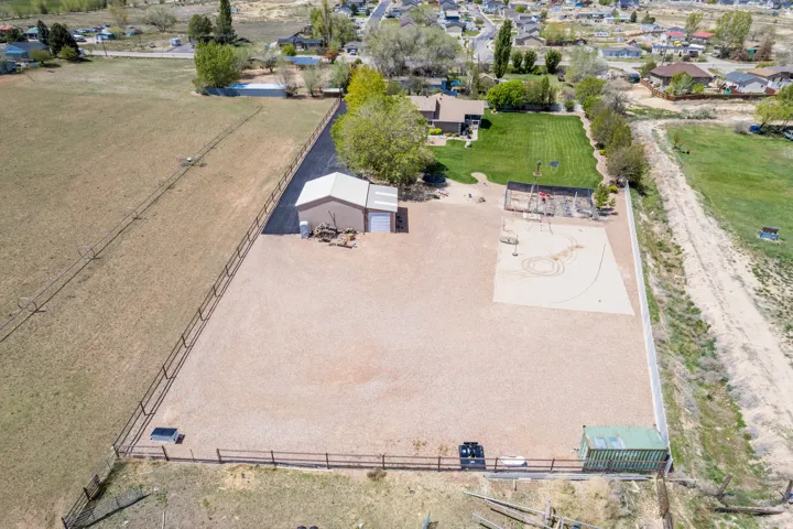 Expansive fenced property featuring a sand volleyball court, a separate gravel-surfaced area, and a large detached garage with two bay doors
