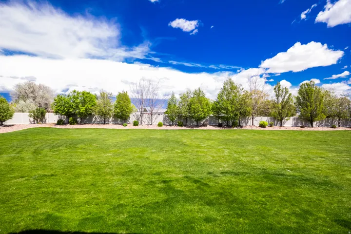 Expansive lawn area bordered by a privacy fence and mature trees