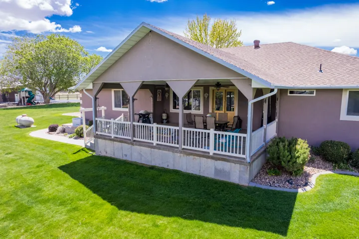 Exterior featuring a covered patio with white railing, stucco siding, and a shingle roof