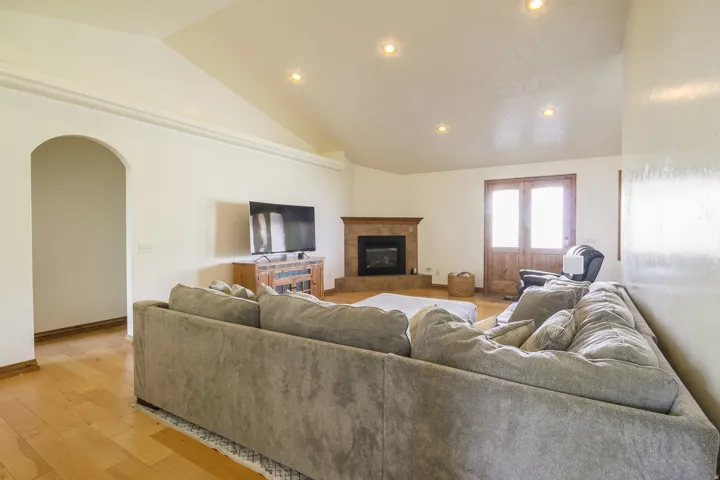 Living area featuring a vaulted ceiling with recessed lighting, wood-finish flooring, and an arched entry