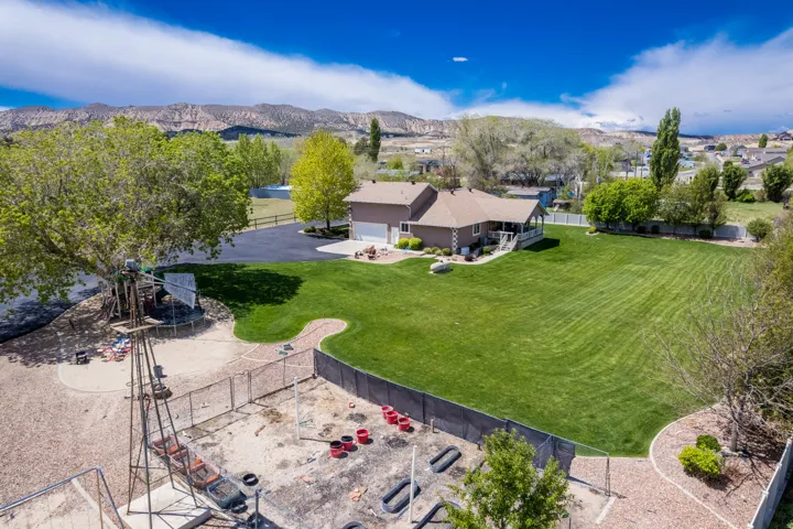 Expansive property featuring a well-maintained lawn, mature trees, and a paved driveway