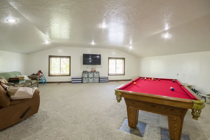 Spacious bonus room featuring an angled ceiling with recessed lighting, two windows with wood trim, and light-toned carpeting