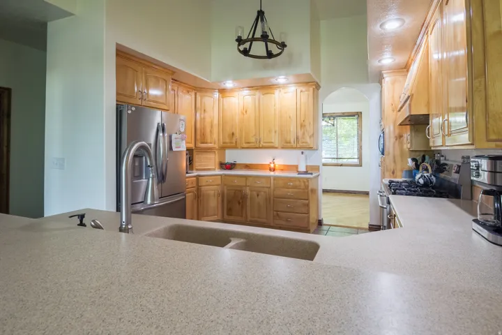 Kitchen featuring a dual-basin sink with a gooseneck faucet, light-toned cabinetry, and stainless steel appliances