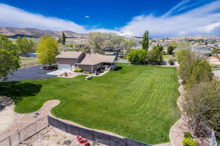 Expansive property with a large green lawn, brown exterior residence, and attached garage
