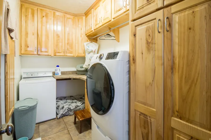 Laundry area featuring natural wood cabinetry and built-in storage