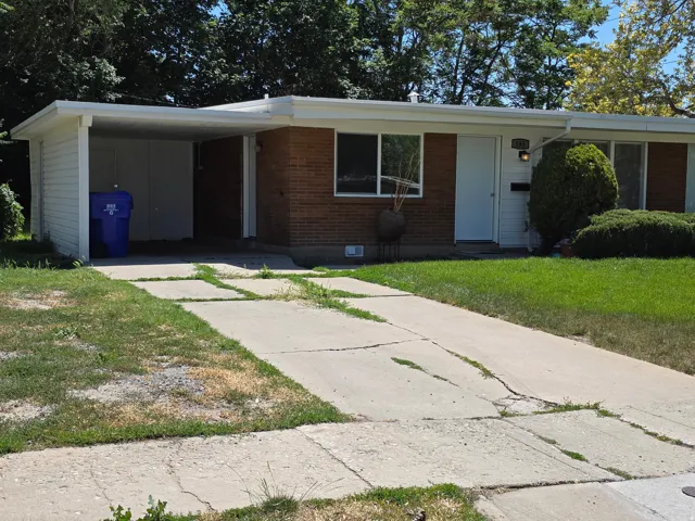View of front of house featuring a front yard, a carport, driveway, and brick siding