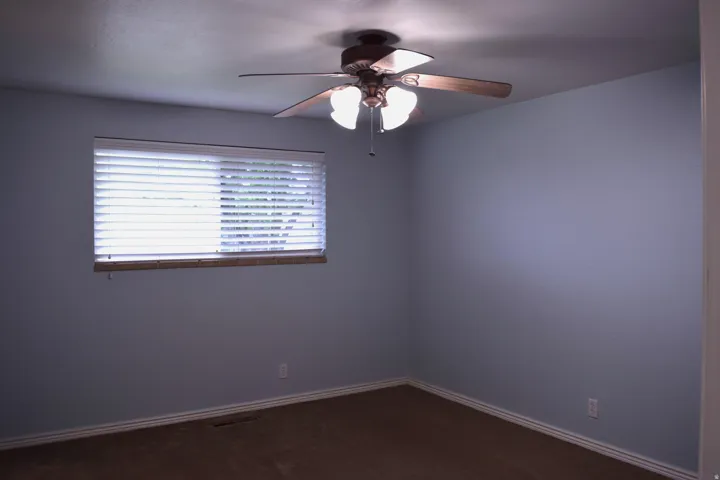 Ceiling fan with light kit, window with horizontal blinds, white baseboards, and brown carpet flooring