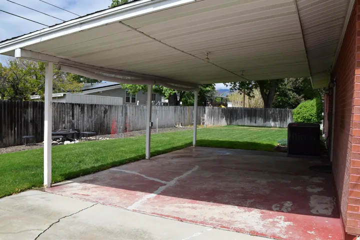 Covered patio area featuring a concrete surface and direct access to a fenced backyard with a grass lawn