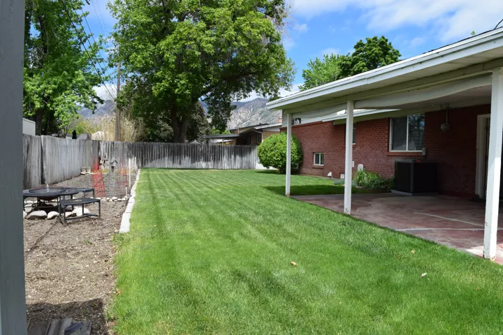 Expansive backyard featuring a manicured lawn, a covered patio, and a brick exterior