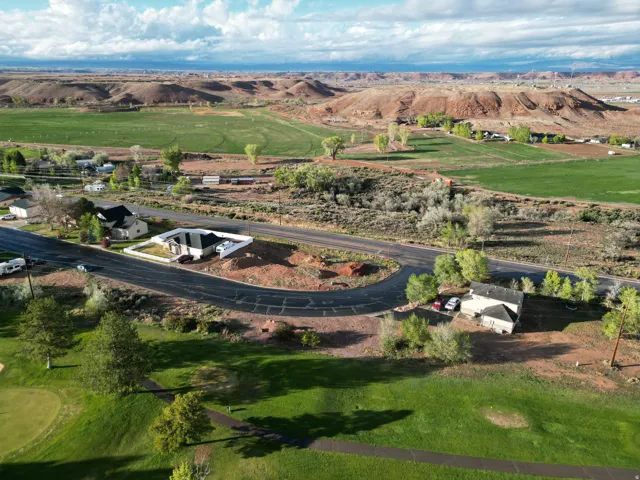 Expansive aerial perspective showcasing varied topography, including green fields and distant red rock formations