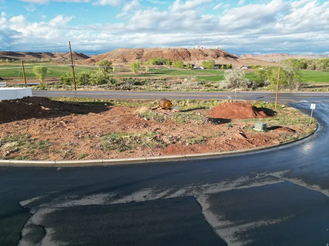 Spacious building lot featuring a paved road, curb, and distant green fields