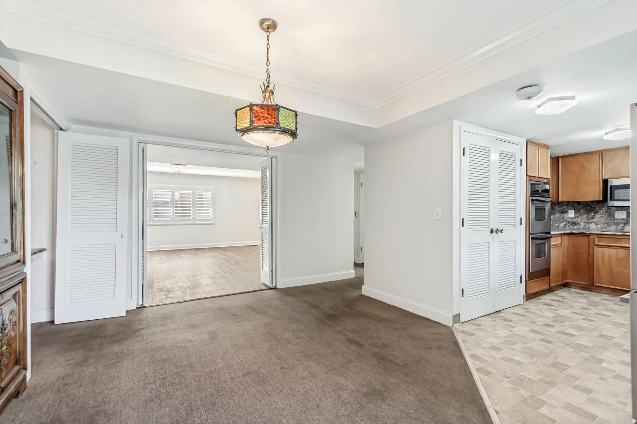 Recessed lighting and crown molding accentuate the ceiling in this open space, featuring a unique stained-glass chandelier