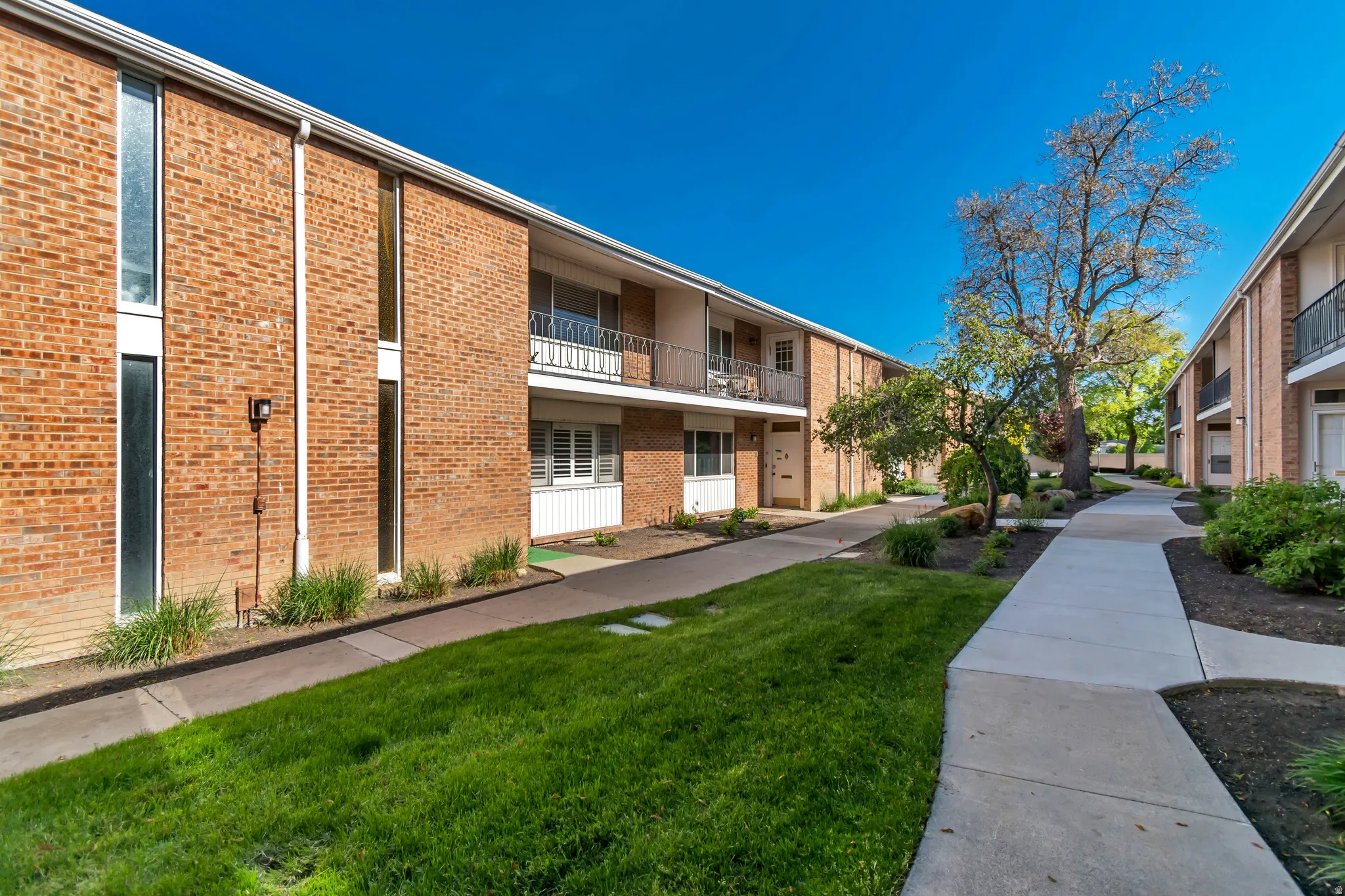Brick exterior with multiple units, each featuring a private balcony or patio