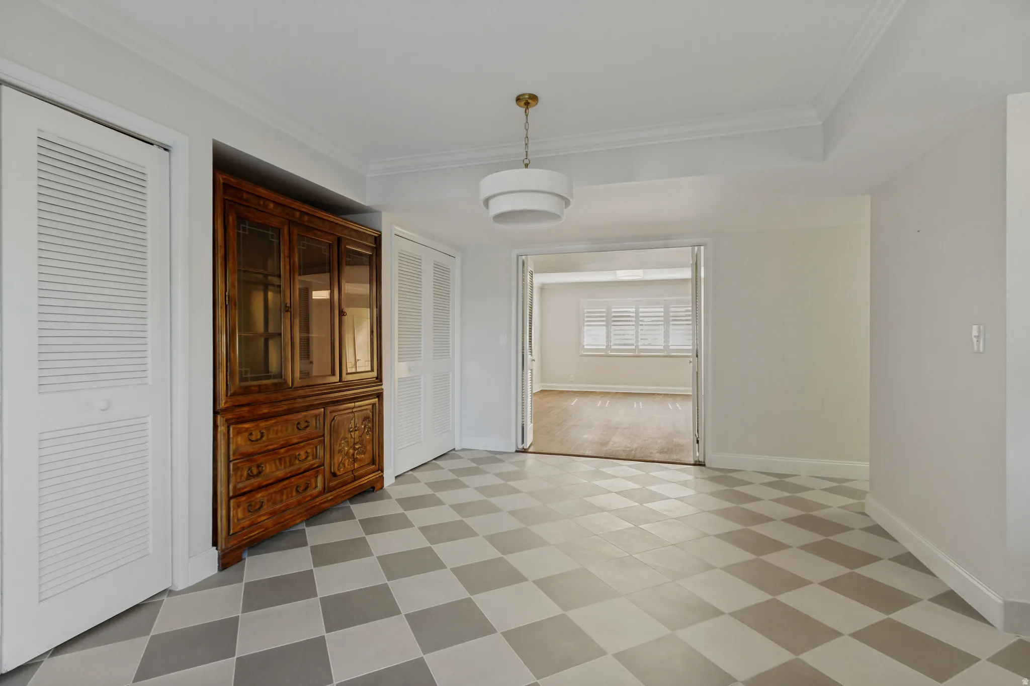 Checkerboard tile flooring, contemporary ceiling light fixture, crown molding, double louvered bifold doors