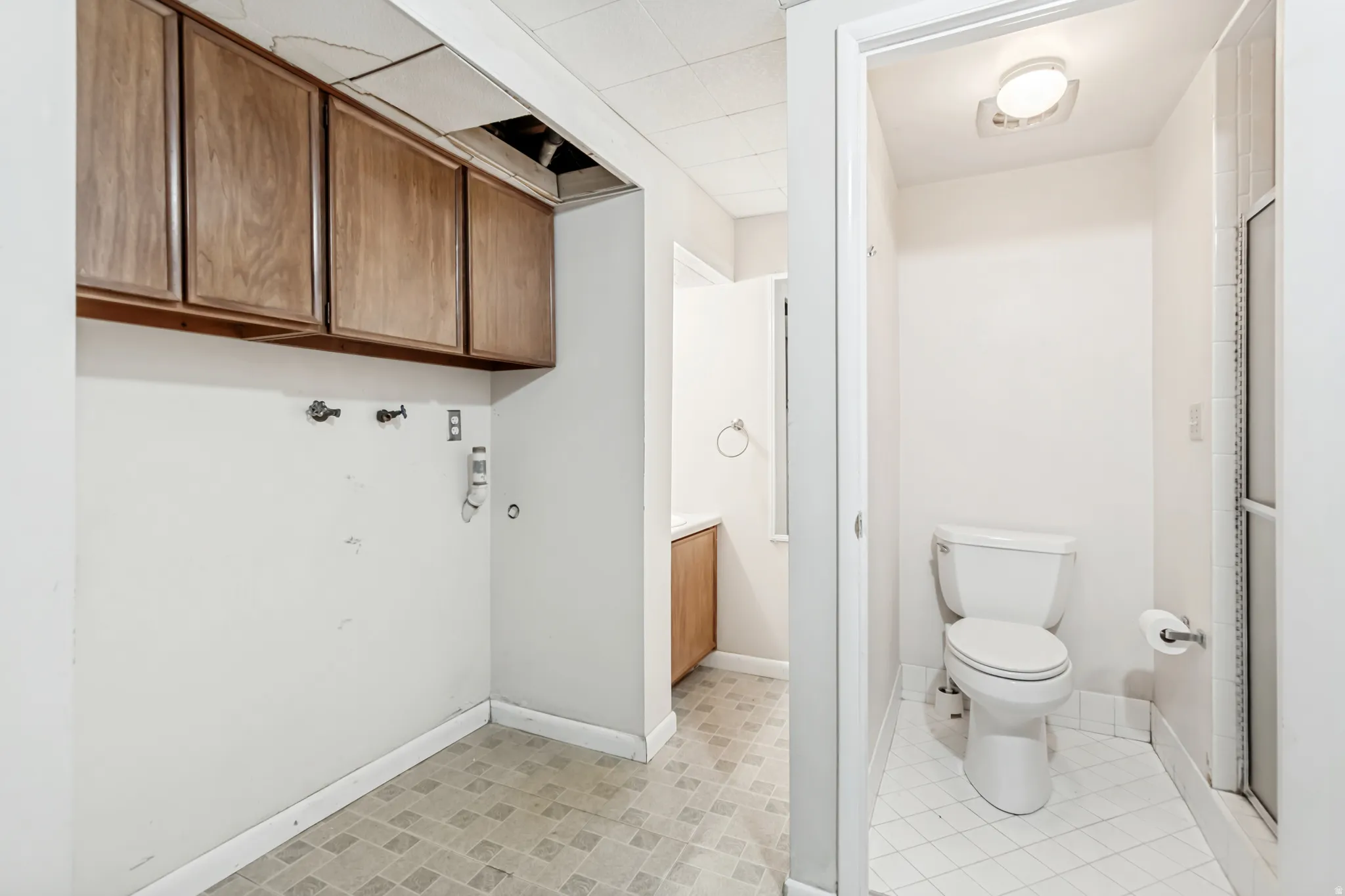 Laundry area featuring wood cabinetry, utility connections, and patterned floor tile