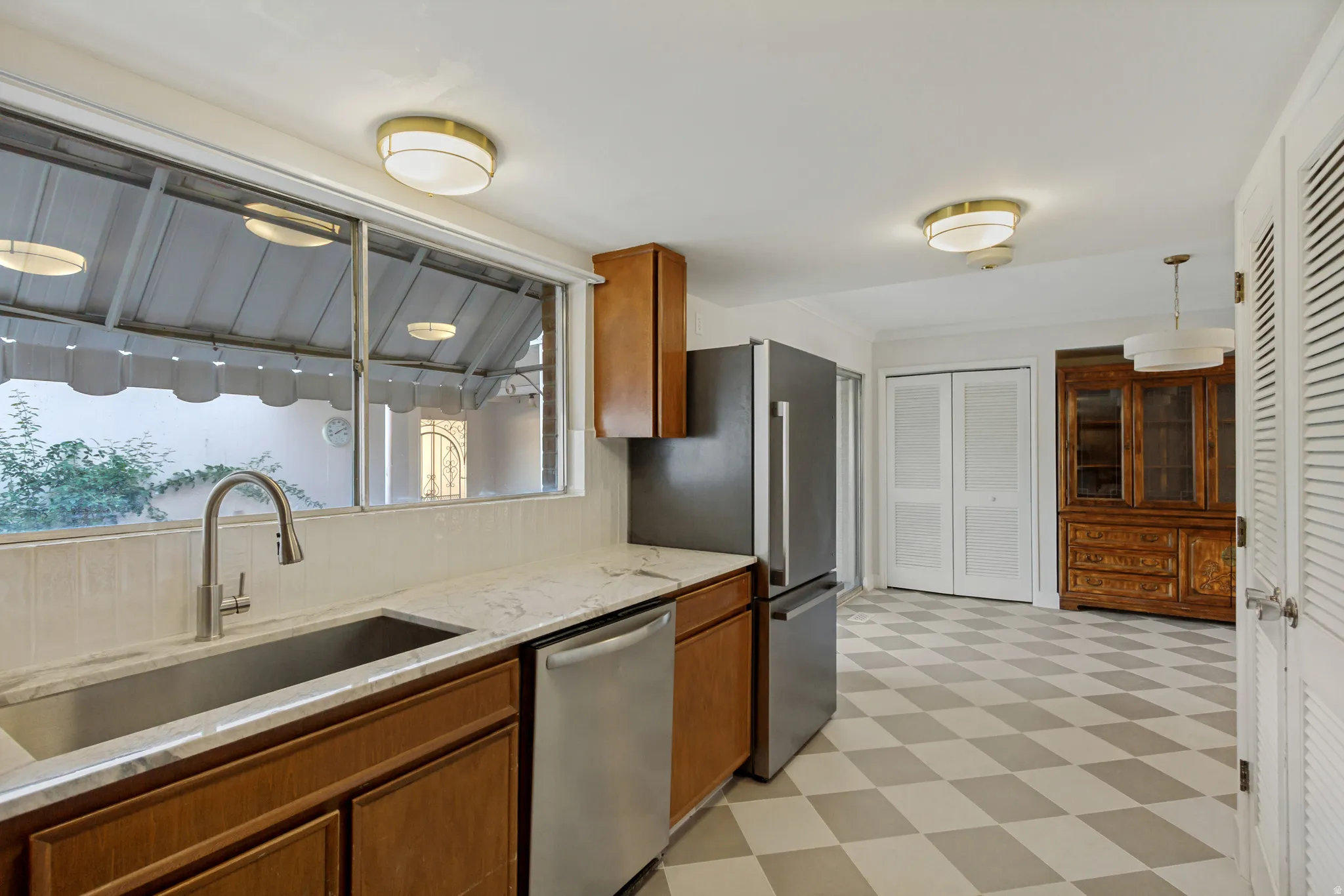 Kitchen featuring wood cabinetry, stainless steel appliances, a large window, checkered flooring, and flush-mount lighting