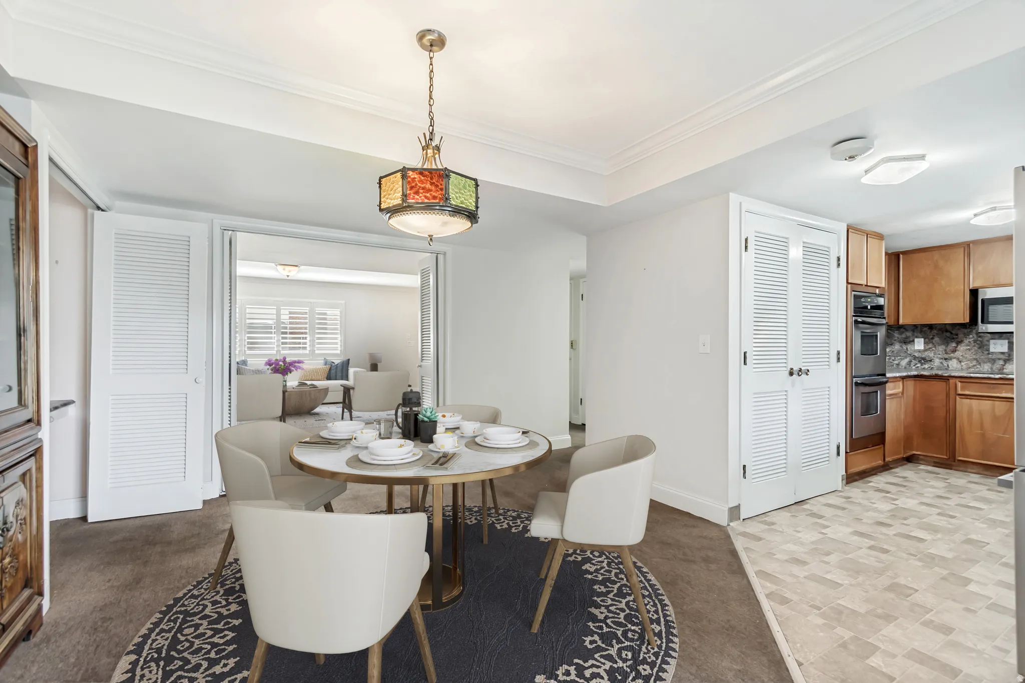 Dining area with a colorful pendant light fixture and decorative crown molding