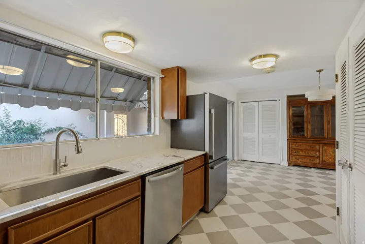 Kitchen featuring wood cabinetry, stainless steel appliances, a large window, checkered flooring, and flush-mount lighting