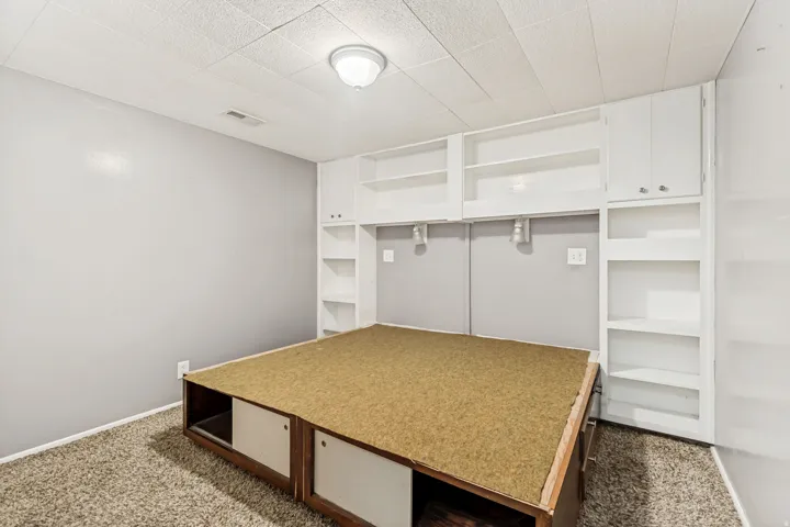 Built-in storage solutions featuring white cabinetry and open shelving, complemented by a textured carpet flooring