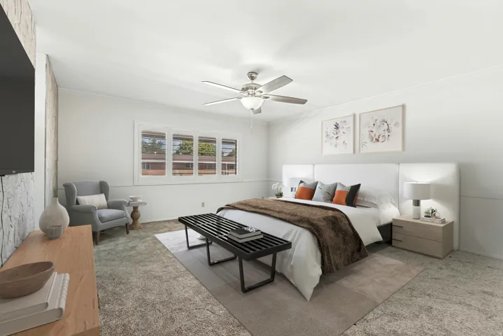 Spacious bedroom featuring a ceiling fan, a large window, a textured accent wall, and light-toned carpeting