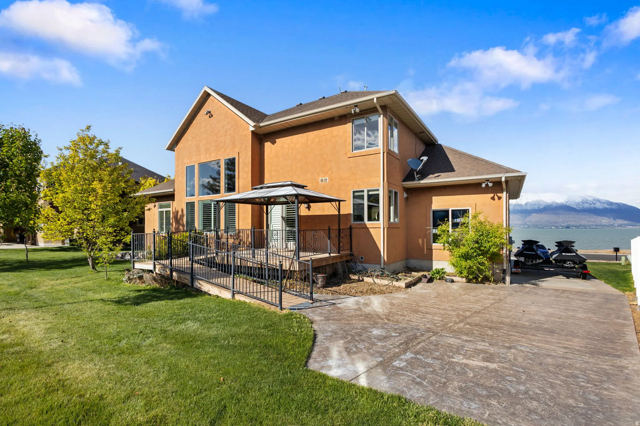 Rear view of house featuring a yard, stucco siding, and a water and mountain view